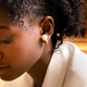A person wearing the gold version of the Nova H1 Audio Earrings.